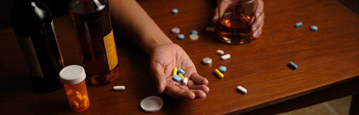 Рука мужчины с таблетками и стаканом алкоголя